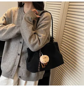 Detailed view of black faux suede tote bag featuring a cute plush bear charm accessory