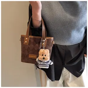 Close-up of brown suede bucket bag with quilted patterns and a cute teddy dog charm