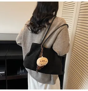 Detail view of black faux suede tote bag with side pleats and a cute bear charm pendant