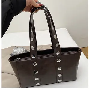 Close-up of coffee brown tote bag featuring silver rivet studs and glossy faux leather