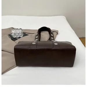 Detailed view of dark brown leather handbag with vintage silver studs on a white background