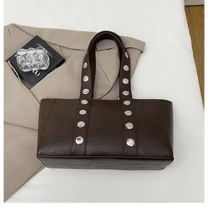 Detail of dark brown leather tote bag with decorative silver metal studs and rivets