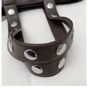 Macro detail of dark brown leather handle with polished silver rivets and stitching