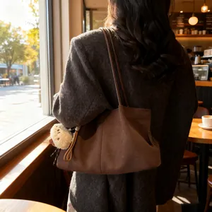Retro brown suede underarm tote bag with plush charm shown in a cozy cafe setting