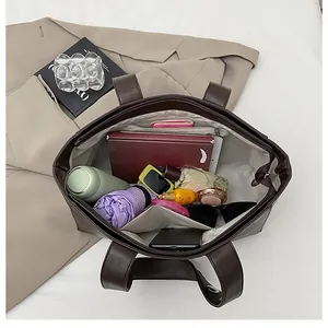 Top view of spacious brown leather tote bag interior showing compartments and daily essentials