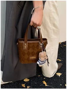 Detail of a brown quilted velvet bucket bag with a cute teddy bear charm pendant