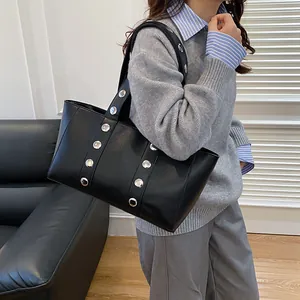 Minimalist black leather tote bag with silver rivets and modern industrial shoulder design