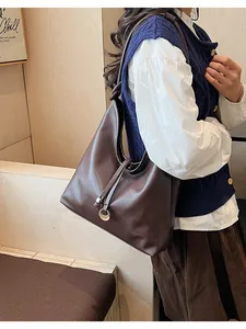 Detail of a dark brown large leather tote bag worn with a casual vest and shirt