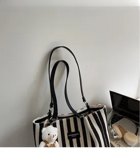 Detail of striped canvas tote bag with fashion leather tag and cute teddy bear charm