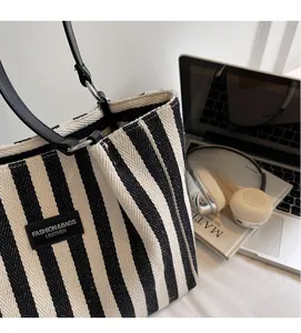 Detail of striped canvas tote with black leather handle and woven fabric texture