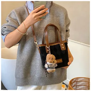 Detailed view of black quilted bucket bag with brown straps and cute teddy bear charm