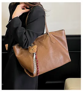 Dettaglio della borsa tote in pelle marrone vintage con morbido ciondolo a orsetto