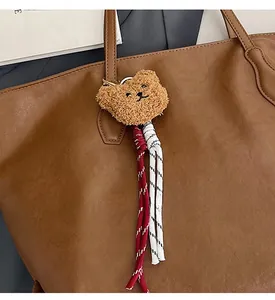 Dettaglio di un ciondolo a forma di orsetto con corde intrecciate su borsa in pelle