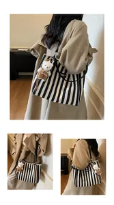 Detail shot of black and white striped canvas tote with a cute bear plush charm and strap