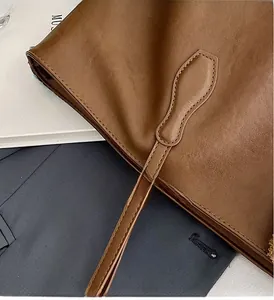 Dettaglio del manico della borsa tote marrone con cuciture rinforzate e texture in pelle