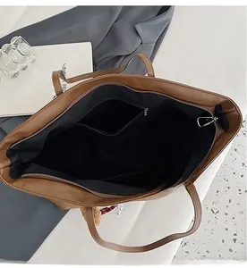 Vista dall'alto dell'interno della borsa tote marrone con più scomparti e ciondolo a pompon