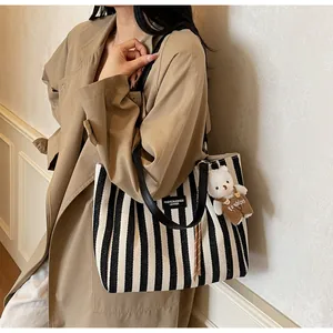 Close-up of black and white striped canvas tote with a cute plush bear charm detail