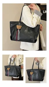 Dettaglio di una grande borsa tote vintage nera con ciondolo a forma di orso e pelle morbida