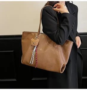 Vista dettagliata della grande borsa tote vintage marrone con ciondolo a orsetto a spalla