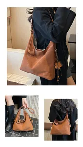 Detail of caramel hobo bag featuring flower tassel charm and minimalist logo branding