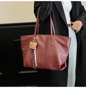 Grande borsa tote bordeaux con ciondolo a forma di orso indossata da modella in blazer