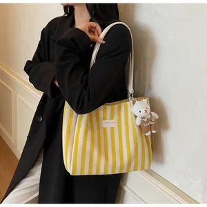 Detail of striped canvas tote with leather label and cute plush bear charm accessory