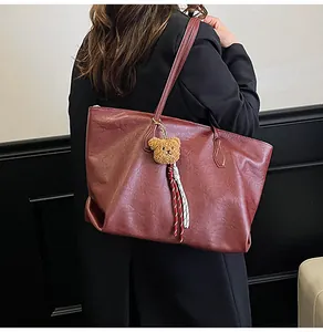 Dettaglio della borsa tote vintage bordeaux con texture in ecopelle lucida e ciondolo