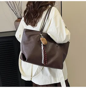 Dettaglio della borsa shopper marrone scuro con ciondolo a orsetto e nappine colorate