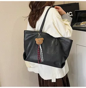 Dettaglio di una borsa tote grande vintage in ecopelle nera con ciondolo a forma di orsetto