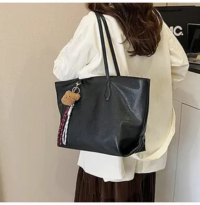 Dettaglio della borsa tote nera retrò con ciondolo a orsetto e nappine colorate