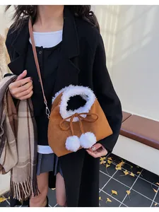 Detail of brown faux suede crossbody bag with white faux fur trim and pom-pom drawstrings