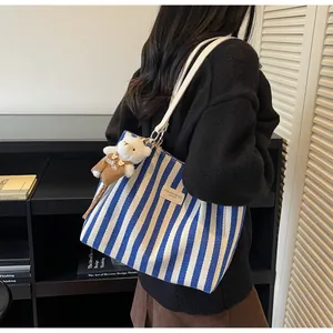 Detail of blue striped canvas tote bag with a cute bear plush charm and leather patch