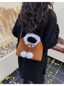 Brown suede crossbody bag with white faux fur trim and decorative pom poms detail
