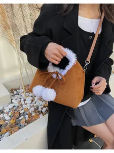 Close-up of brown suede bag featuring white faux fur trim and cute pom-pom drawstrings