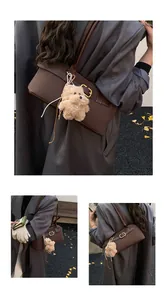 Detail of dark brown leather underarm bag with gold buckles and plush dog charm