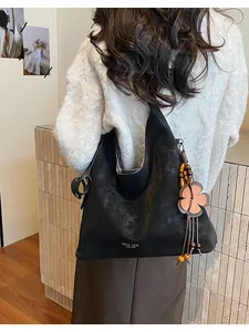 Detail of black large capacity hobo bag featuring retro flower charm and matte leather texture