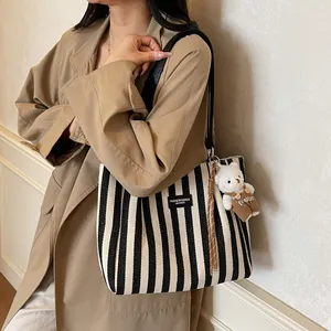 Striped canvas tote bag with black leather straps and a cute plush bear pendant accessory