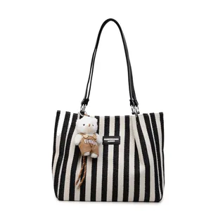 Striped canvas tote bag with black leather straps and cute plush bear charm decoration