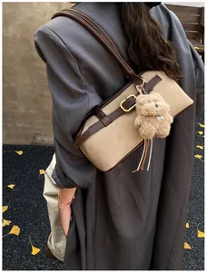 Detail of vintage tote bag with deep brown leather strap and cute teddy bear pendant charm