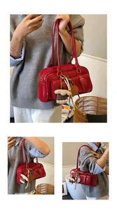 Close-up of red patent leather shoulder bag with plush lamb and heart pendant detail