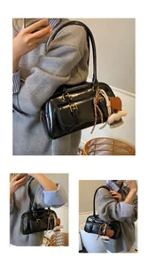 Detail of black patent leather underarm bag with gold hardware and plush charm