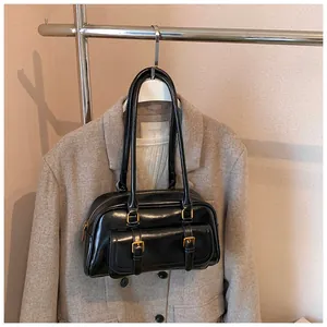 Detail of black vintage shoulder bag with dual handles and gold metallic buckles