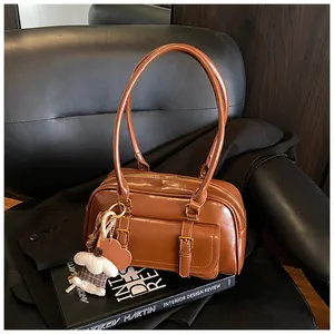 Detail of vintage brown leather underarm bag with double buckle pockets and plush bear charm