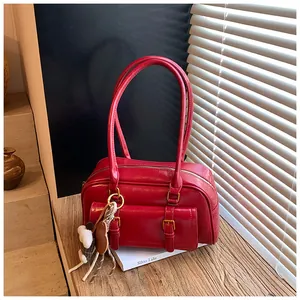 Close-up of red retro leather pillow bag with double-buckle pocket and bear charm