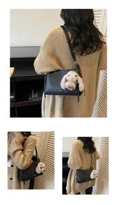 Detail of black leather shoulder bag featuring a plush rabbit charm and metal logo