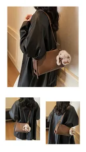 Brown vintage underarm bag with a plush rabbit pendant shown on a model's shoulder