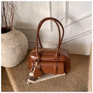 Close-up of retro brown leather shoulder bag with gold buckles and heart charm