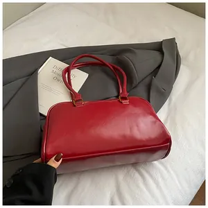 Detailed view of glossy red underarm bag with gold metal hardware and smooth leather