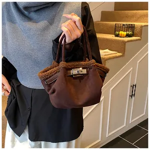 Detail of dark brown suede bucket bag with faux fur trim and silver turn-lock buckle
