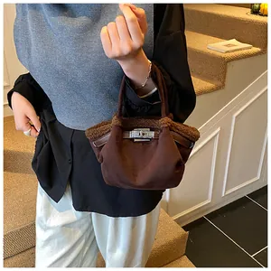 Detail of a brown bucket bag with faux shearling trim and silver metal twist lock